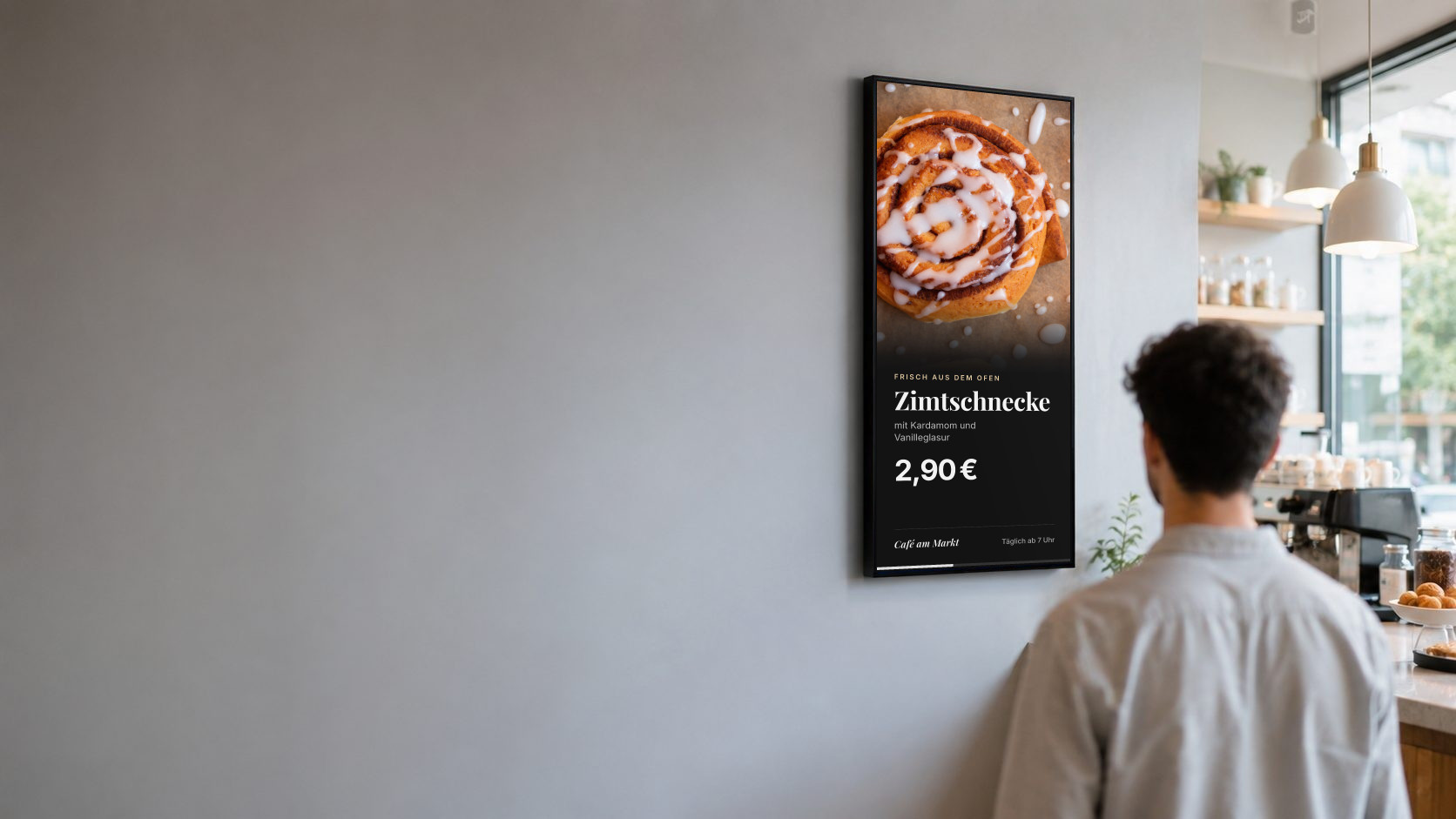 Ein Gast schaut auf den Bildschirm über der Theke eines Cafés